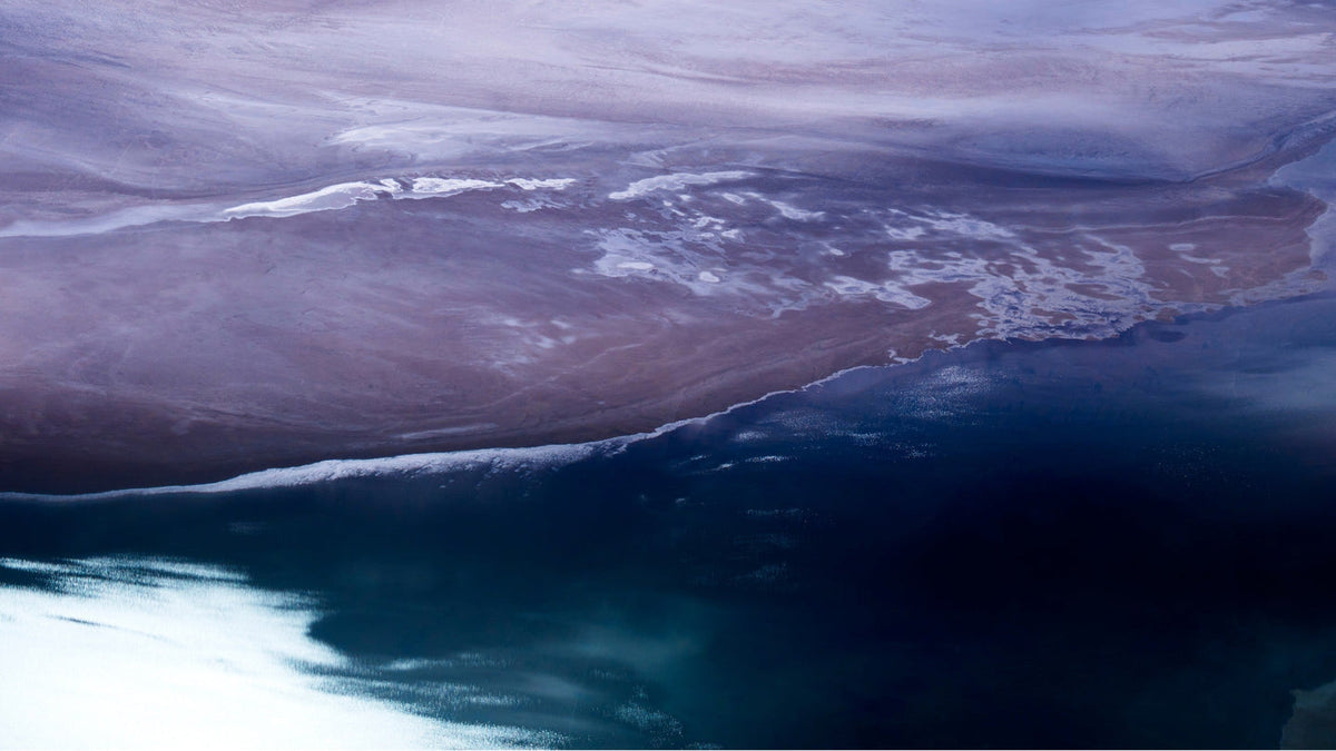 Aerial image of Coral Bay, Western Australia, where the pale sands of the Pilbara meet the deep indigo of the Indian Ocean at the edge of Ningaloo Reef.