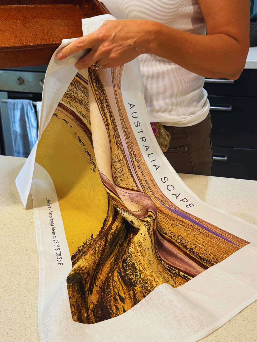 Australia Scape designer tea towel in 100% linen depicting the shimmering country of Lake Eyre in gold, tan and ochre tones.