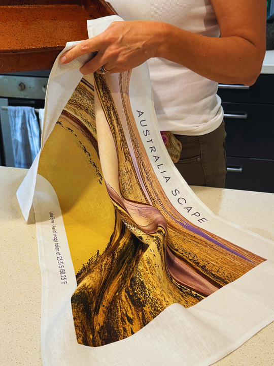 Australia Scape designer tea towel in 100% linen depicting the shimmering country of Lake Eyre in gold, tan and ochre tones.